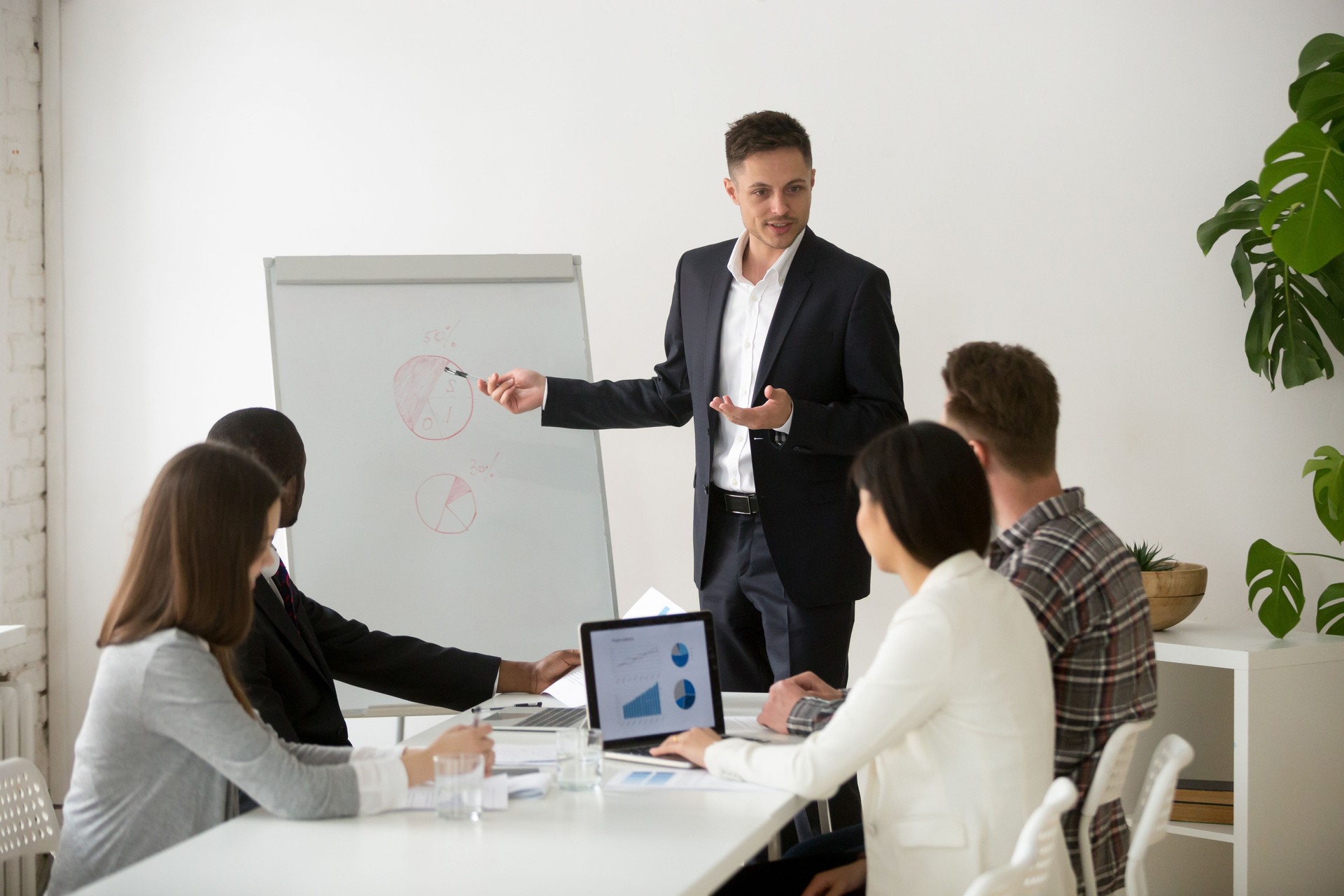 Successful team leader presenting new project to employees at meeting